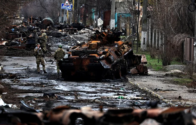 Vojak fotografira svojega tovariša, ko pozira ob uničenem ruskem tanku in oklepnih vozilih med rusko invazijo na Ukrajino v Buči. FOTO: Zohra Bensemra/Reuters
