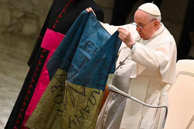 Papež Frančišek z ukrajinsko zastavo v rokah. FOTO: Andreas Solaro/AFP
