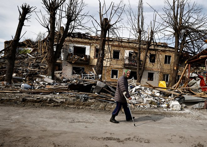 Ženska hodi mimo stavbe v Borodjanki, ki so jo uničile ruske granate. FOTO: Zohra Bensemra/Reuters
