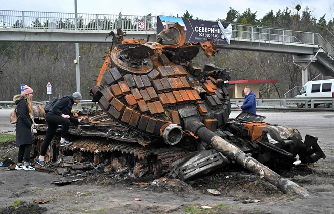 Prebivalci vasi Buzova zahodno od Kijeva ob uničenem ruskem tanku. FOTO: Sergei Supinsky/AFP