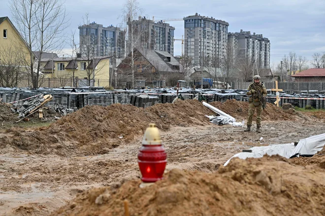 Ukrajinski stražar ob množičnem grobišču v Buči. FOTO: Sergei Supinsky/AFP