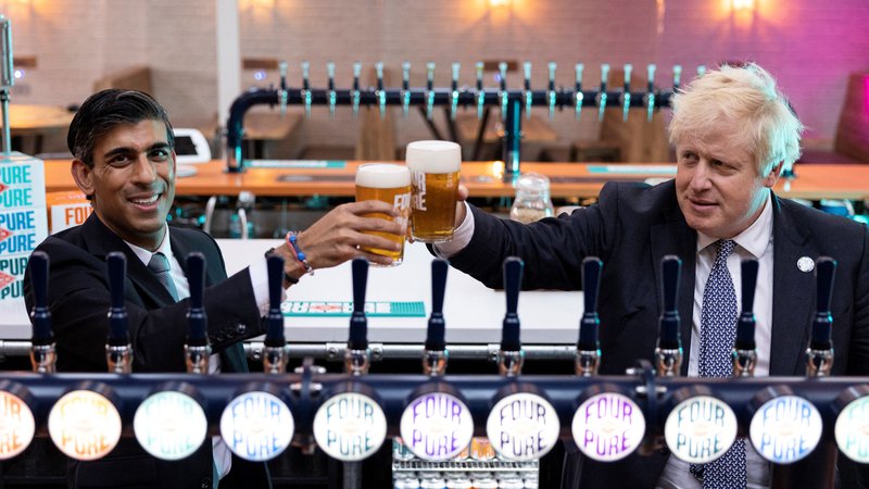 Fotografija: Britanski premier Boris Johnson in finančni minister Rishi Sunak med nazdravljanjem v eni od londonskih pivovarn leto dni zatem, ko sta z udeležbo na rojstnodnevni zabavi kršila protikovidne ukrepe. Foto: Dan Kitwood/AFP
