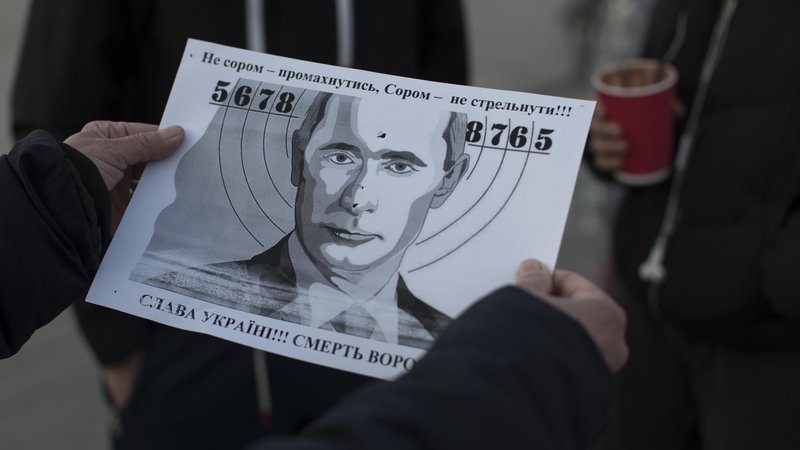 Fotografija: Na Trgu kralja Danila mimoidoči s plastično kalašnikovko streljajo v tarčo s podobo Vladimirja Putina. FOTO: Jure Eržen/Delo
