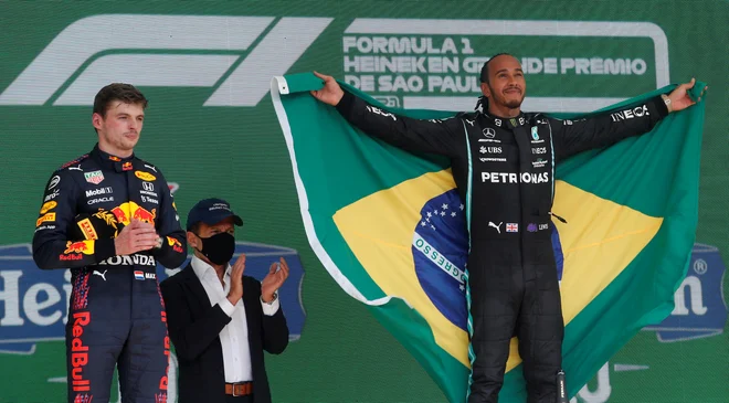 Lewis Hamilton je lani po zmagi v Interlagosu na oder prinesel brazilsko zastavo. FOTO: Amanda Perobelli/Reuters