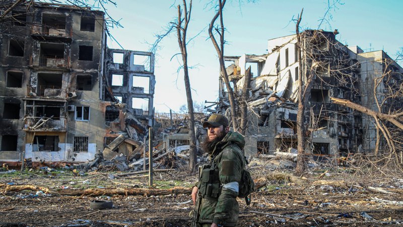 Fotografija: Čečenski vojak pozira fotografu pred uničenimi stanovanjskimi stavbami v Mariupolju. FOTO: Reuters
