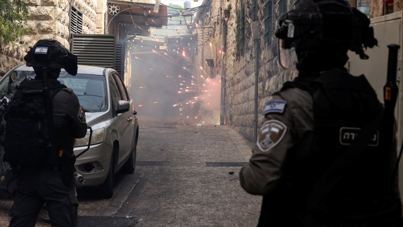 Fotografija: Palestinci mečejo petarde in ognjemetne rakete, izraelska mejna policija pa odgovarja. FOTO: Ammar Awad/Reuters
