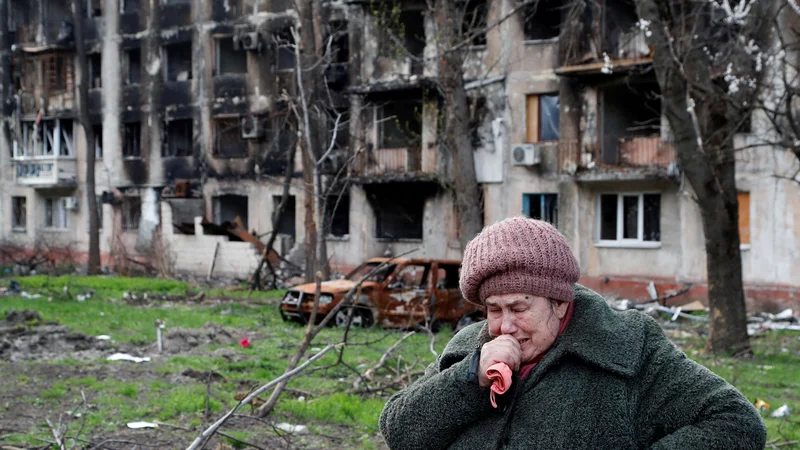Tamara, ki ima 71 let, stoji pred svojim popolnoma porušenim stanovanjskim blokom v Mariupolju. FOTO:&nbsp;Aleksander Jermočenko/ Reuters
