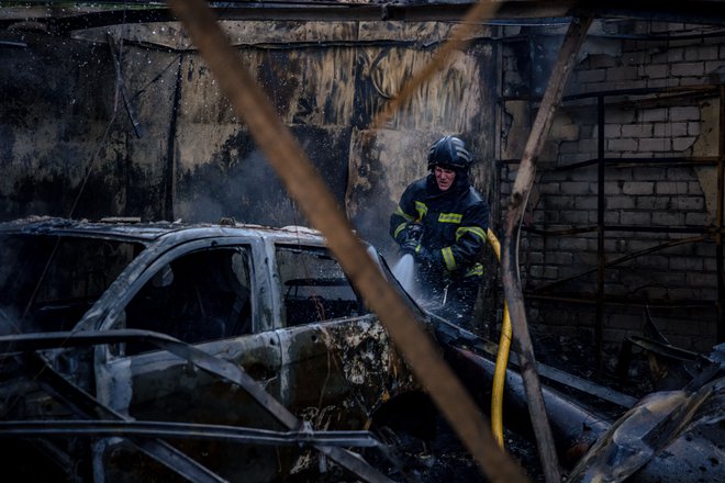 Gasilec se spopada s požarom, ki je v Harkovu izbruhnil po obstreljevanju. FOTO: Dimitar Dilkoff/Afp
