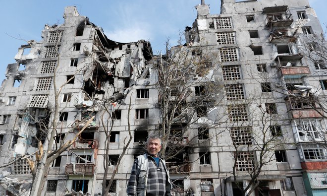 Lokalni prebivalec pred uničeno stavbo v Mariupolju. FOTO: Aleksander Ermočenko/Reuters
