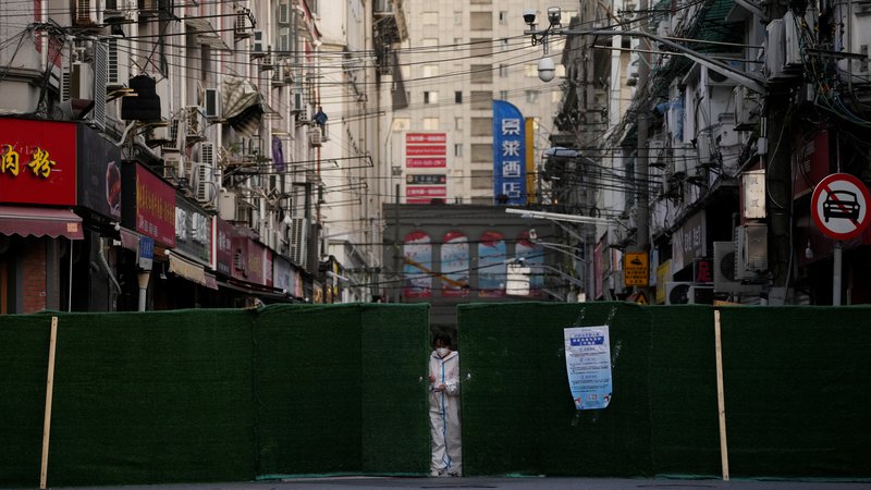 Fotografija: Na fotografiji oseba v zaščitni opremi, ki med strogim zaprtjem javnega življenja zapira ulično pregrado. FOTO: Aly Song/Reuters
