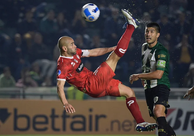 Čilski nogometaš Union La Calera, Argentinec Sebastian Saez, je na spektakularen način zabil edini gol proti argentinskemu Banfieldu na nogometni tekmi skupinskega dela Južnoameriškega pokala v Banfieldu. Foto: Juan Mabromata/Afp
