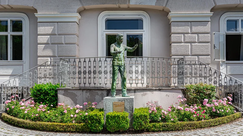 Fotografija: Kip dirigenta Herberta von Karajana obiskovalce pozdravlja z vrta njegove rojstne hiše, od koder se odpira lep pogled na Salzburg. FOTO: Shutterstock