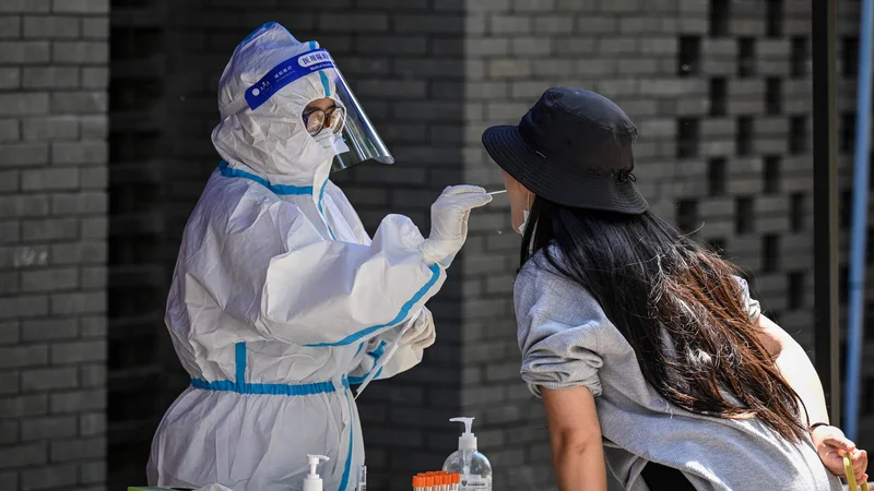 Fotografija: Sobotni odvzem brisa v Pekingu. FOTO: Jade Gao/AFP