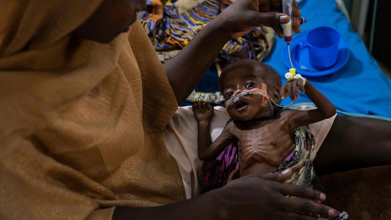 Fotografija: Mariam Ali hrani svojega podhranjenega sina Alija na oddelku za kritično bolne v bolnišnici v Čadu. Povečanje števila primerov podhranjenosti je posledica več dejavnikov. Covid-19 je povzročil dvig cen, kmetijska proizvodnja v zadnjem letu je bila slabša kot v zadnjih petih letih, zdaj pa se zaradi vojne v Ukrajini hitro zvišujejo cene osnovnih živil. Enota ima zmogljivosti za 60 bolnikov, vendar jih sprejema 100, saj število primerov še naprej narašča. Normalno je največ primerov podhranjenosti julija in avgusta, zato se bojijo, da bo enota do takrat popolnoma preobremenjena, saj so zmogljivosti že presežene, pravi vodja operativne podpore iz nevladne organizacije ALIMA, ki jo financira EU. Foto Andrew Caballero-reynolds Afp
