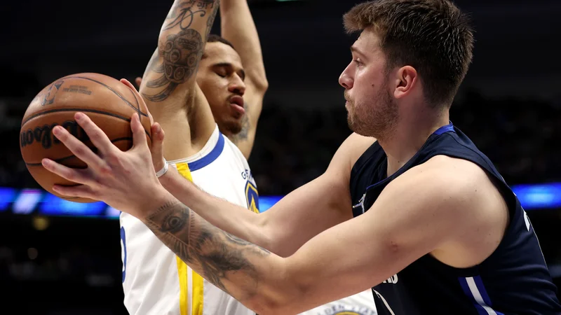 Luka Dončić v prodoru ob Juanu Toscano-Andersonu na tretji tekmi konferenčnega finala v Dallasu. FOTO: Tom Pennington/AFP