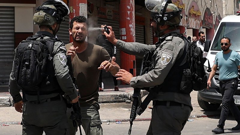 Fotografija: V mestu Hauwara na Zahodnem bregu med spopadi je izraelski mejni policist palestinskemu protestniku v obraz brizgnil solzivec. Foto: Jaafar Ashtiyeh/Afp
