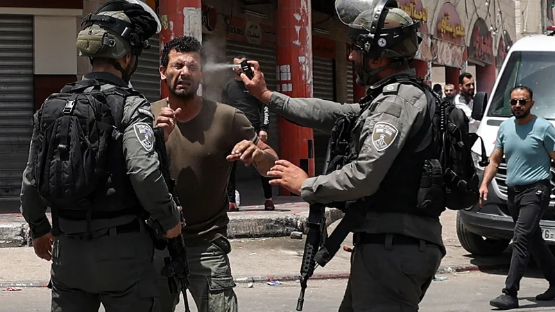 Fotografija: V mestu Hauwara na Zahodnem bregu med spopadi je izraelski mejni policist palestinskemu protestniku v obraz brizgnil solzivec. Foto: Jaafar Ashtiyeh/Afp
