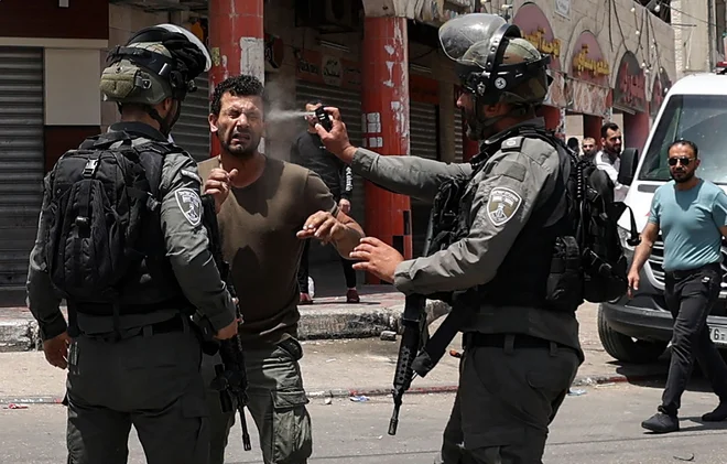 V mestu Hauwara na Zahodnem bregu med spopadi je izraelski mejni policist palestinskemu protestniku v obraz brizgnil solzivec. Foto: Jaafar Ashtiyeh/Afp