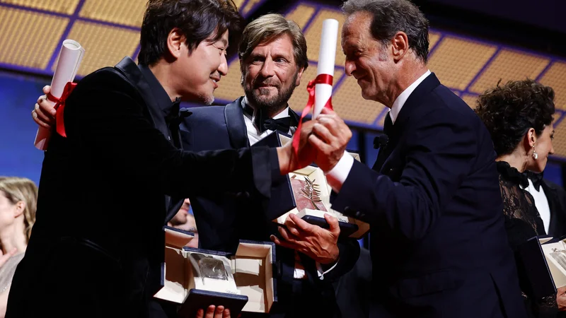 Fotografija: Song Kang-ho, najboljši igralec, režiser Ruben Ostlund z zlato palmo za najboljši film in Vincent Lindon, predsednik žirije. FOTO: Sarah Meyssonnier/Reuters