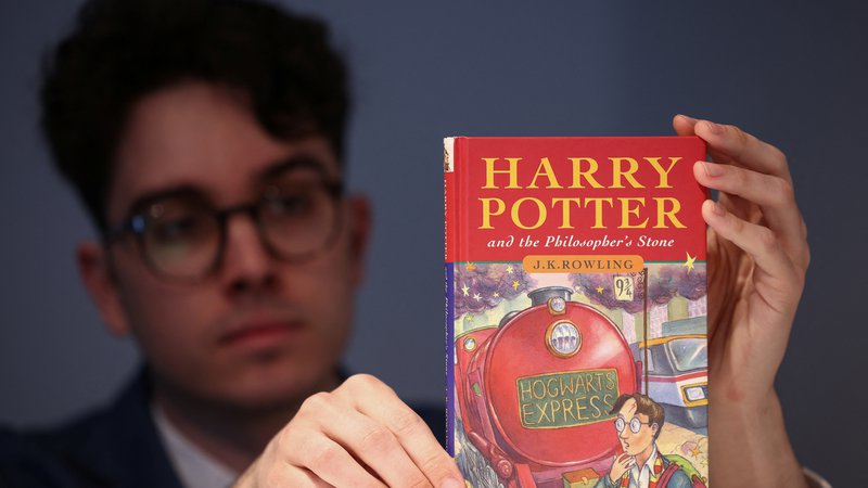 Fotografija: Mark Wiltshire z enim od redkih kopij prve knjihe o mladem čarodeju Harryju Potterju. FOTO: Henry Nicholls/Reuters
