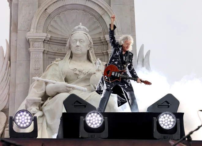 Legendarni kitarist skupine The Queen Brian May se je tokrat dvignil do naročja kipa kraljičine praprababice, vladarice Viktorije. FOTO: Jonathan Buckmaster/Reuters
