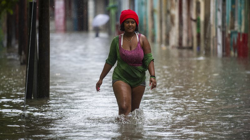 Fotografija: Ženska se prebija po poplavljeni ulici v Havani. - Ostanek orkana Agatha je v zahodnih in osrednjih provincah Kube povzročl intenzivno in vztrajno deževje. Foto: Yamil Lage/Afp
