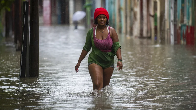 Fotografija: Ženska se prebija po poplavljeni ulici v Havani. - Ostanek orkana Agatha je v zahodnih in osrednjih provincah Kube povzročl intenzivno in vztrajno deževje. Foto: Yamil Lage/Afp
