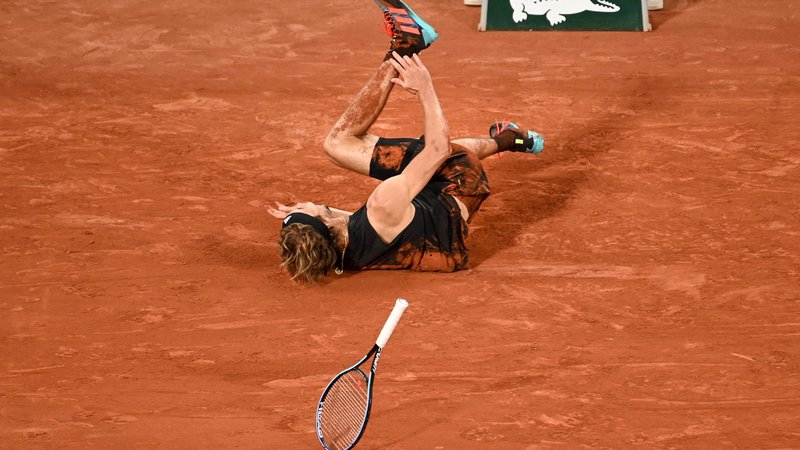 Fotografija: Alexander Zverev je dvoboj z Rafaelom Nadalom končal v krikih bolečine in igrišče zapustil na vozičku. FOTO: Tomas Stevens/AFP

