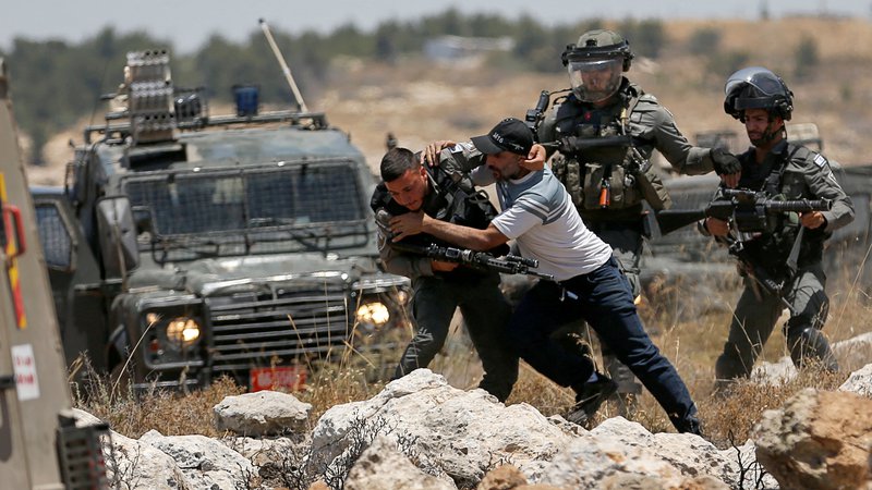 Fotografija: Palestinec se spopada z izraelskimi silami med protestom proti izraelskemu naseljevanju v bližini Hebrona na Zahodnem bregu, ki ga zaseda Izrael. Foto: Mussa Issa Qawasma/Reuters
