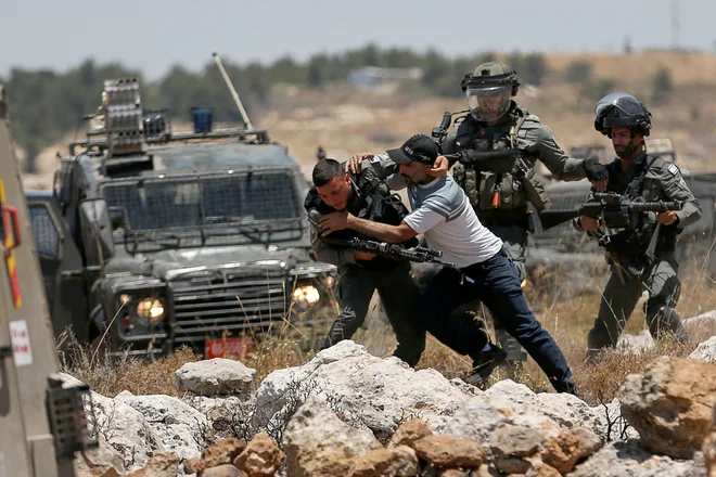 Palestinec se spopada z izraelskimi silami med protestom proti izraelskemu naseljevanju v bližini Hebrona na Zahodnem bregu, ki ga zaseda Izrael. Foto: Mussa Issa Qawasma/Reuters