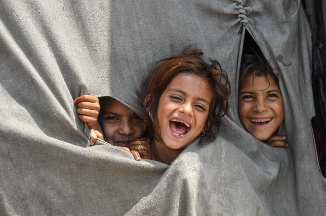 Otroci afganistanskih beguncev, ki živijo v Pakistanu, se zabavajo v začasnem šotoru na obrobju Lahoreja, na predvečer svetovnega dneva beguncev. Foto: Arif Ali/Afp