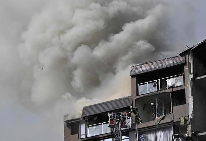 FOTO: Reševalna akcija po raketiranju v Kijevu. FOTO: Genya Savilov/AFP
