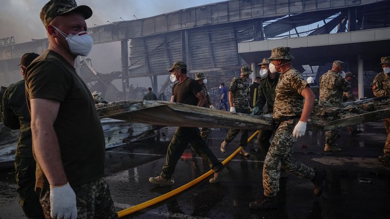 Fotografija: Reševalci in vojaki med odstranjevanjem posledic ruskega napada na nakupovalno središče v ukrajinskem Kremenčuku. FOTO: Reuters
