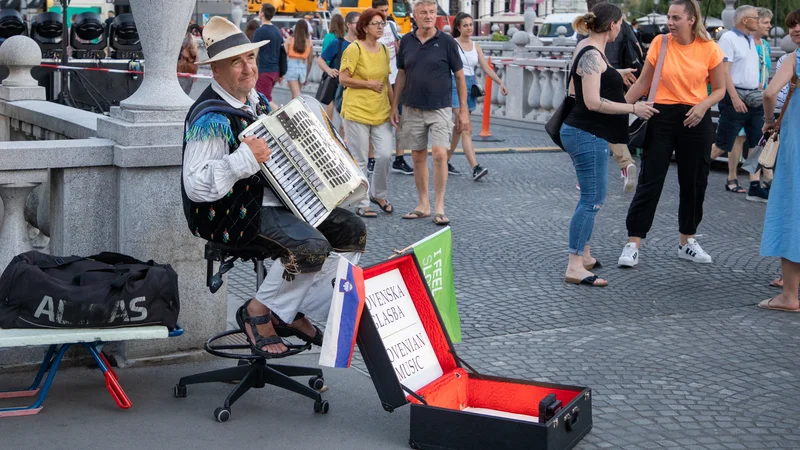Harmonikar na Tromostovju je postal maskota prestolnice, a njegova navzočnost marsikoga moti. FOTO: Voranc Vogel/Delo
