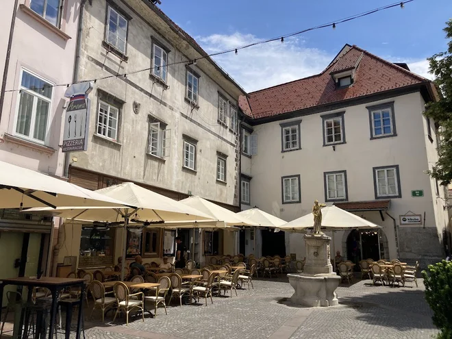 Najstarejša hiša v Ljubljani je stisnjena med dve drugi, pred njo je vodnjak Dekleta z vrčem. Fotografije Jaroslav Jankovič
