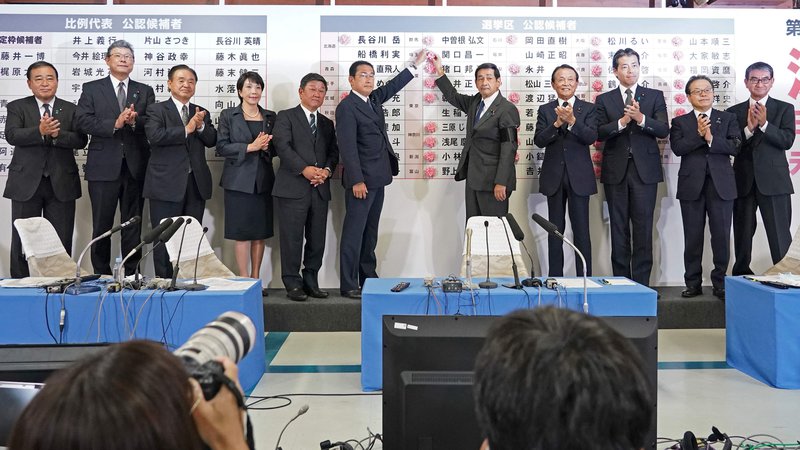 Fotografija: Premier in predsednik liberalnodemokratske stranke Fumio Kišida (v sredini levo) v znamenje zmage na volitvah v zgornji dom dieta – parlamenta – na listo strankinih kandidatov pripenja rdeče rože iz papirja. FOTO: Toru Hanai/Afp
