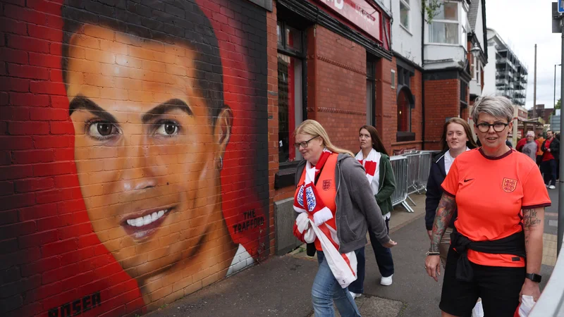 Navijači pred tekmo ženskega eura 2022 v okolici manchestrskega štadiona&nbsp;Old Trafford, kjer je Cristiano Ronaldo prisoten tudi kot umetnina. FOTO: Lee Smith/Reuters
