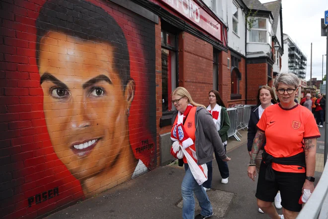Navijači pred tekmo ženskega eura 2022 v okolici manchestrskega štadiona&nbsp;Old Trafford, kjer je Cristiano Ronaldo prisoten tudi kot umetnina. FOTO: Lee Smith/Reuters

