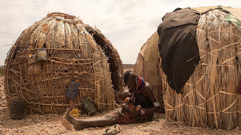 Fotografija: Ženska doji svojega otroka pred začasno hišo na območju Loiyangalani, kjer živijo družine, ki jih je prizadela dolgotrajna suša v Marsabitu. Najmanj 18 milijonov ljudi v Keniji in okoliških državah se sooča s hudo lakoto, saj regijo pustoši najhujša suša v zadnjih 40 letih. Več kot štiri milijone jih je na pogosto pozabljenem kenijskem severu, število pa se letos vztrajno povečuje tudi zaradi finančne krize. Foto: Simon Maina/Afp

