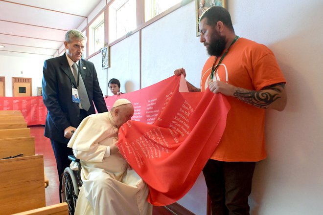 Frančišek je poljubil izjemno dolg trak, na katerem so izpisana imena žrtev v internatih, ki jih je vodila Katoliška cerkev. FOTO: Vatican Media/AFP
