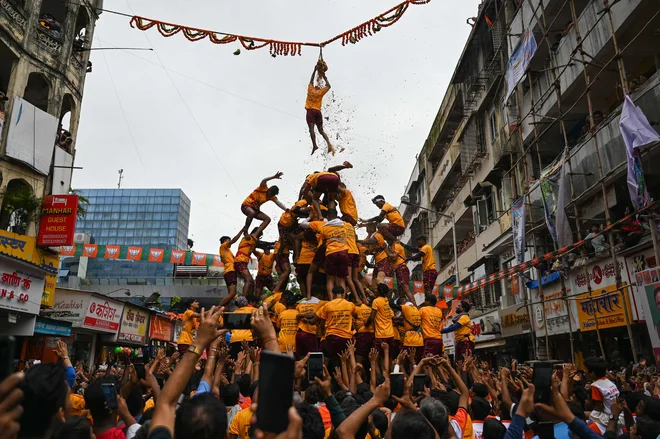 V Mumbaju se je mlad hindujski vernik obesil na vrv, potem ko je razbil lonček s skuto, ki visi v zraku, medtem ko se je pod njim zrušila človeška piramida med praznovanjem festivala Janmashtami, ki zaznamuje rojstvo hindujskega boga Krišne. Foto: Punit Paranjpe/Afp
