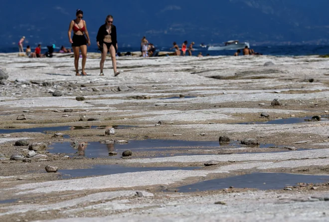 Gardsko jezero je dobilo povsem drugačno podobo. Razkrile so se velike bele skale, ki pa so ponekod zelo spolzke in zato nevarne za obiskovalce. FOTO: Flavio Lo Scalzo/Reuters
