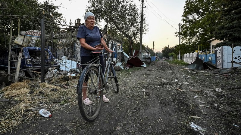 Fotografija: Ženska stoji blizu stanovanjskih hiš, uničenih zaradi ruskega vojaškega napada v Čaplinu. FOTO: Reuters

