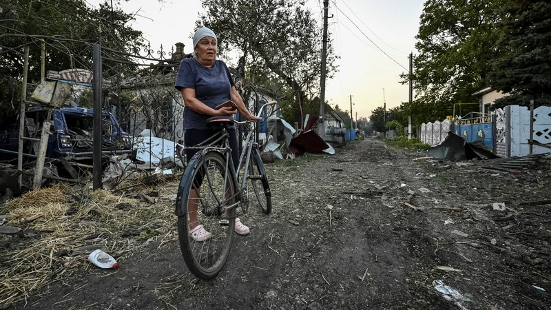 Fotografija: Ženska stoji blizu stanovanjskih hiš, uničenih zaradi ruskega vojaškega napada v Čaplinu. FOTO: Reuters
