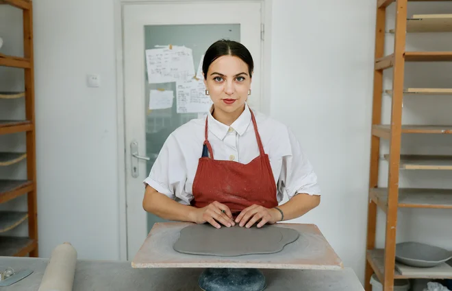 Najprej zgnetem glino, jo razvaljam, potem pa jo počasi sušim. Počasno sušenje mi omogoča, da oblikujem krivine, da oblikujem krožnik z zaobljenim robom, ki ga obdrži med sušenjem. FOTO: Blaž Samec/Delo

