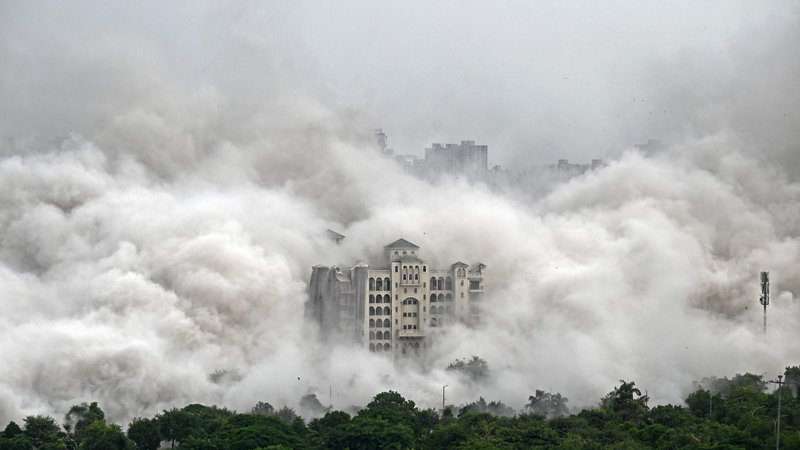Fotografija: Stanovanjska soseska na obrobju New Delhija je zajeta v prah, potem ko so mestne oblasti z nadzorovano eksplozijo porušile 100 metrov visoka nezakonito zgrajena stanovanjska stolpa »Twin Towers«. To je bil redek ukrep zoper gradbenike, ki se izmikajo in goljufajo nič hudega sluteče kupce stanovanj. Foto: Sajjad Hussain Afp
