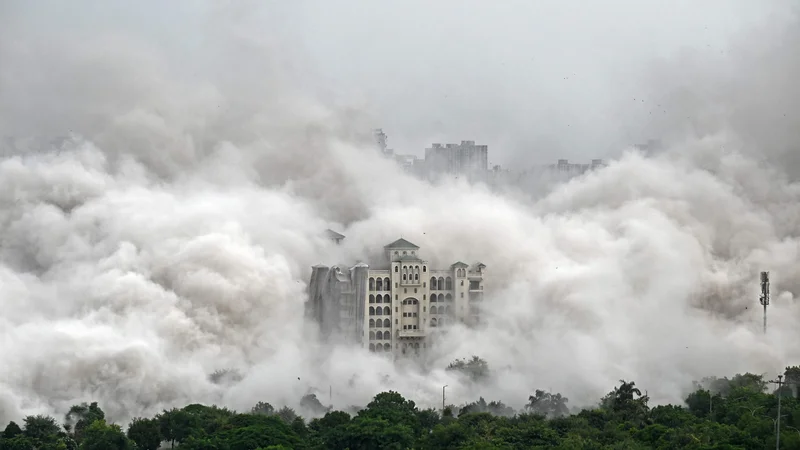 Fotografija: Stanovanjska soseska na obrobju New Delhija je zajeta v prah, potem ko so mestne oblasti z nadzorovano eksplozijo porušile 100 metrov visoka nezakonito zgrajena stanovanjska stolpa »Twin Towers«. To je bil redek ukrep zoper gradbenike, ki se izmikajo in goljufajo nič hudega sluteče kupce stanovanj. Foto: Sajjad Hussain Afp