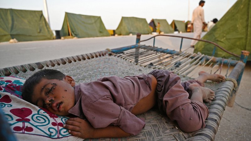 Fotografija: Na obrazu dečka, ki spi pred šotorom v začasnem taborišču v pakistanski provinci Sindh, je polno muh. Skoraj tretjina Pakistana je pod vodo (območje v velikosti Združenega kraljestva) po mesecih rekordnega monsunskega deževja, v katerem je umrlo 1300 ljudi ter odplaknilo več kot milijon domov. Foto: Aamir Qureshi/Afp
