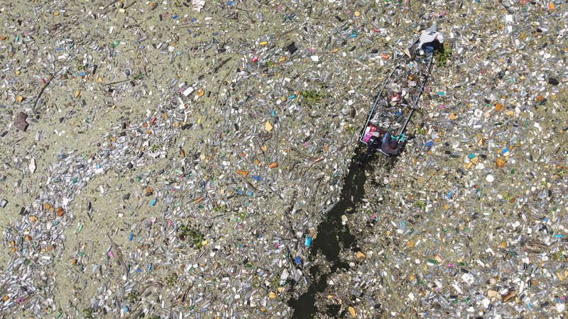 Fotografija: Na salvadorskem rezervoarju Cerron Grande v mestu Potonico moški zbirajo odpadno plastiko, steklo in druge materiale. Ogromne raznobarvne plastične usedline, ki priplavajo iz različnih pritokov, kot odeja prekrivajo mirne vode jezera Suchitlan. Enako se dogaja na rajskih plažah honduraškihh Karibov, na katere iz Gvatemale prihaja na tisoče ton odpadkov. Foto: Camilo Freedman/Afp
