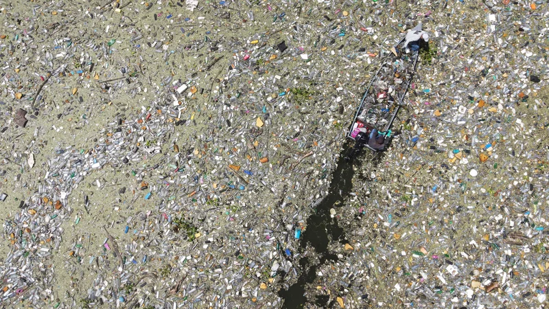 Fotografija: Na salvadorskem rezervoarju Cerron Grande v mestu Potonico moški zbirajo odpadno plastiko, steklo in druge materiale. Ogromne raznobarvne plastične usedline, ki priplavajo iz različnih pritokov, kot odeja prekrivajo mirne vode jezera Suchitlan. Enako se dogaja na rajskih plažah honduraškihh Karibov, na katere iz Gvatemale prihaja na tisoče ton odpadkov. Foto: Camilo Freedman/Afp
